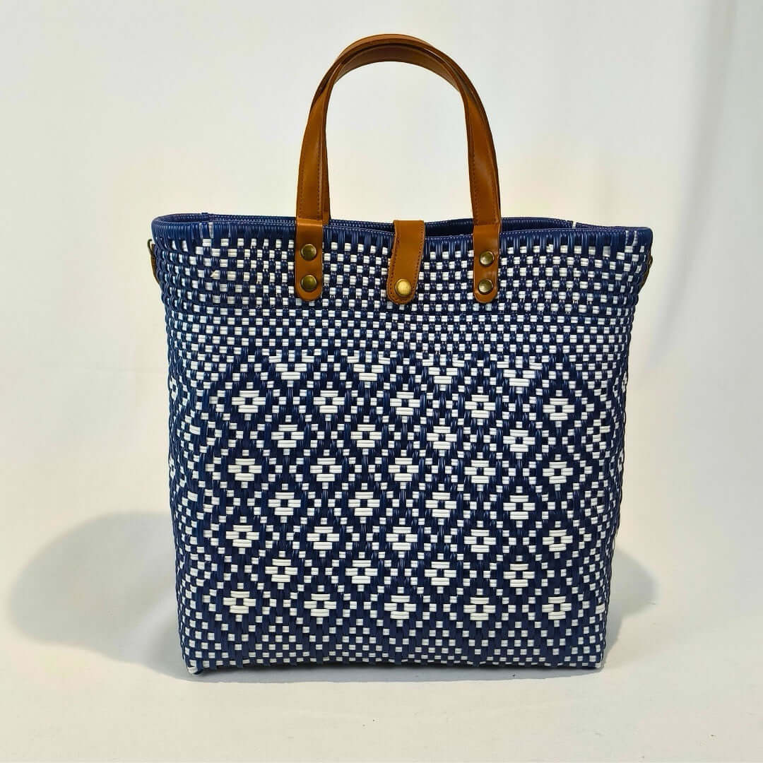 Bolsa artesanal grande color azul claro, tejida a mano con toquilla obtenida del reciclado de plástico y detalles en piel sintética color marrón. Diseño exclusivo con textura geométrica, ideal para uso diario o como accesorio de moda sostenible, hecho en México con material plástico reciclado, toquilla.