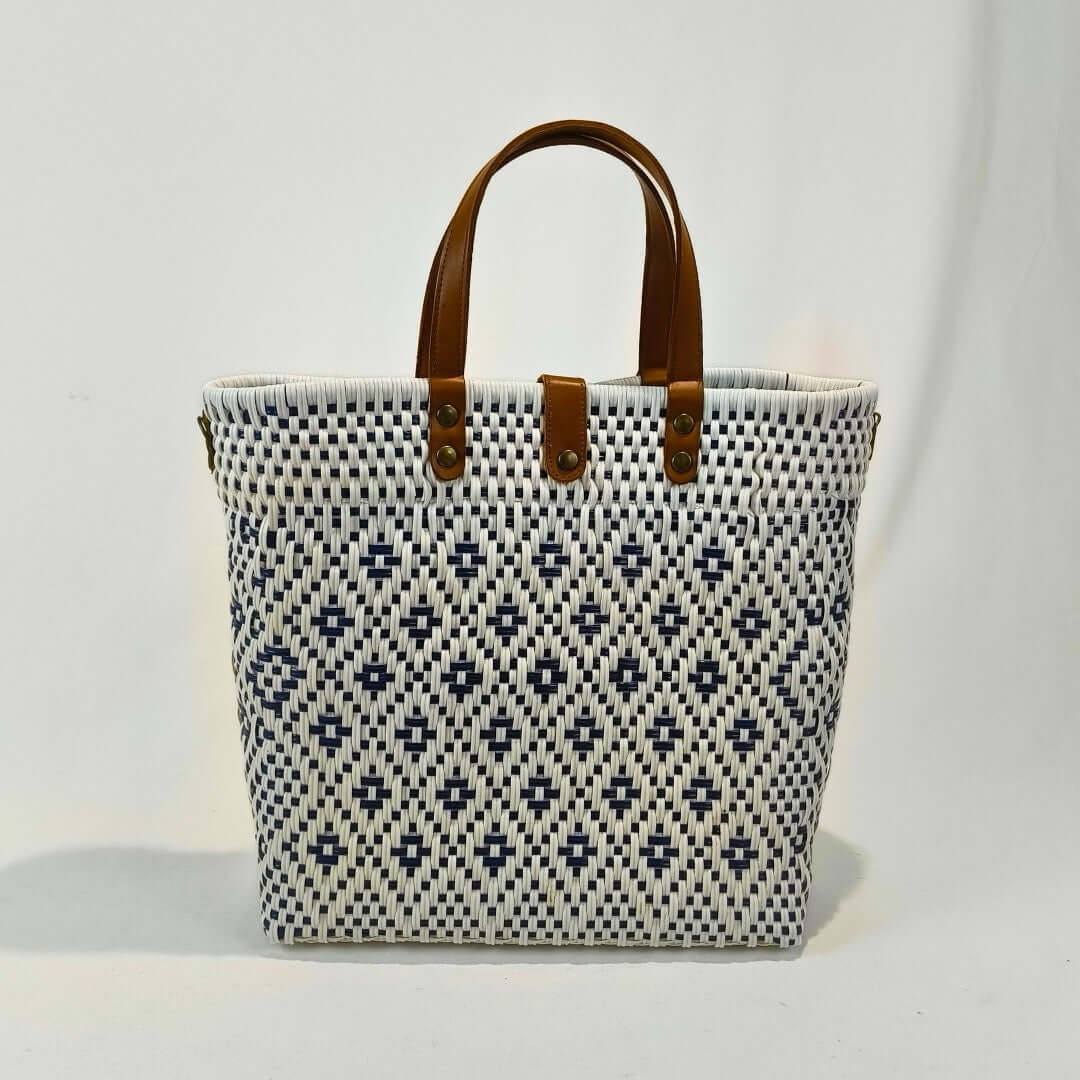 Bolsa artesanal grande color blanco, tejida a mano con toquilla obtenida del reciclado de plástico y detalles en piel sintética color marrón. Diseño exclusivo con textura geométrica, ideal para uso diario o como accesorio de moda sostenible, hecho en México con material plástico reciclado, toquilla.