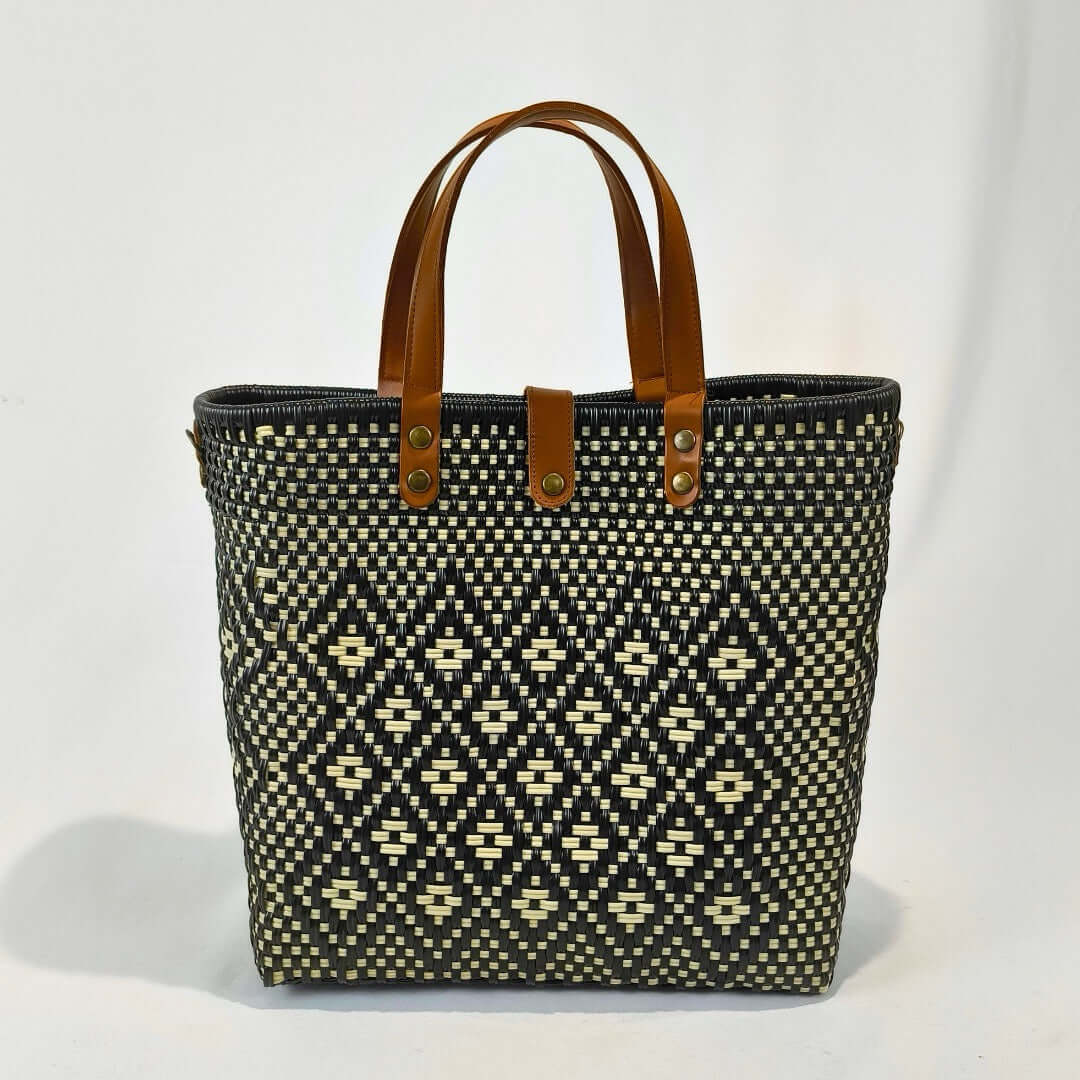 Bolsa artesanal grande color negro, tejida a mano con toquilla obtenida del reciclado de plástico y detalles en piel sintética color marrón. Diseño exclusivo con textura geométrica, ideal para uso diario o como accesorio de moda sostenible, hecho en México con material plástico reciclado, toquilla.