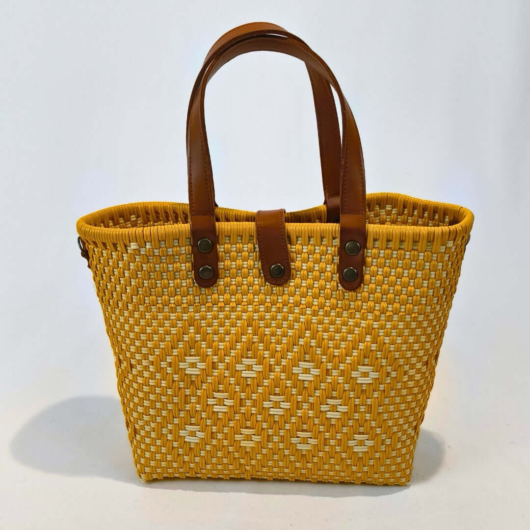 Bolsa artesanal mediana color amarillo, tejida a mano con toquilla obtenida del reciclado de plástico y detalles en piel sintética color marrón. Diseño exclusivo con textura geométrica, ideal para uso diario o como accesorio de moda sostenible, hecho en México con material plástico reciclado, toquilla.