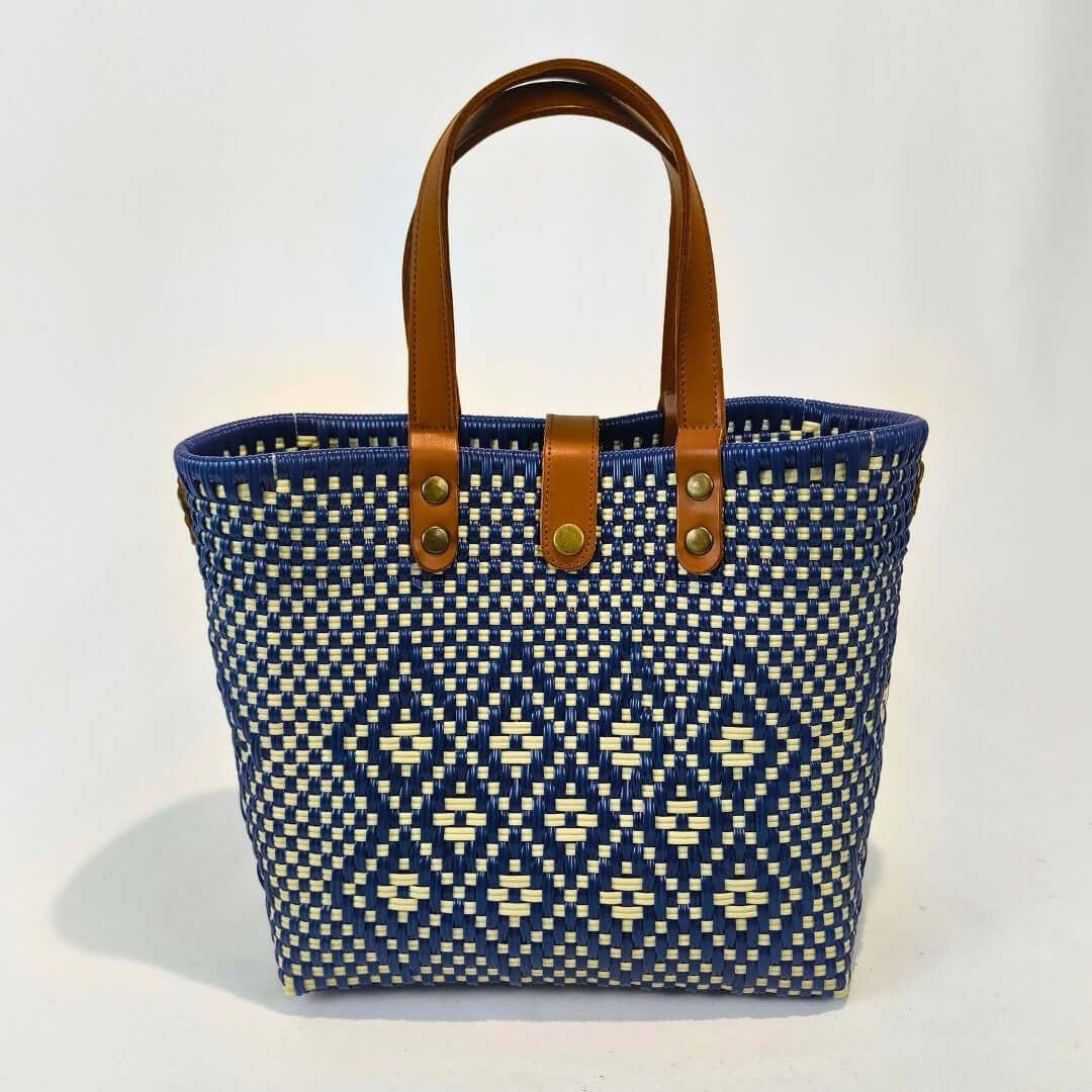 Bolsa artesanal mediana color azul y beige, tejida a mano con toquilla obtenida del reciclado de plástico y detalles en piel sintética color marrón. Diseño exclusivo con textura geométrica, ideal para uso diario o como accesorio de moda sostenible, hecho en México con material plástico reciclado, toquilla.