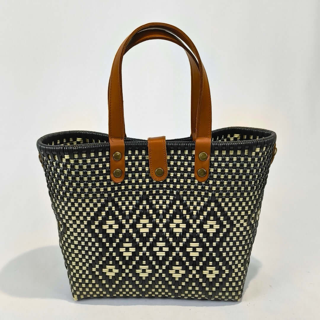 Bolsa artesanal mediana color café y negro, tejida a mano con toquilla obtenida del reciclado de plástico y detalles en piel sintética color marrón. Diseño exclusivo con textura geométrica, ideal para uso diario o como accesorio de moda sostenible, hecho en México con material plástico reciclado, toquilla.