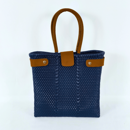 Bolsa artesanal tipo tote clásica color azul rey, tejida a mano con toquilla obtenida del reciclado de plástico. Cuenta con asas y detalles en piel sintética color café, diseño elegante y funcional ideal para uso diario o como accesorio de moda sostenible, hecho en México con material plástico reciclado, toquilla, tejida en penales mexicanos.